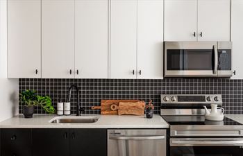 a kitchen with white cabinets and a black and white tile backsplash