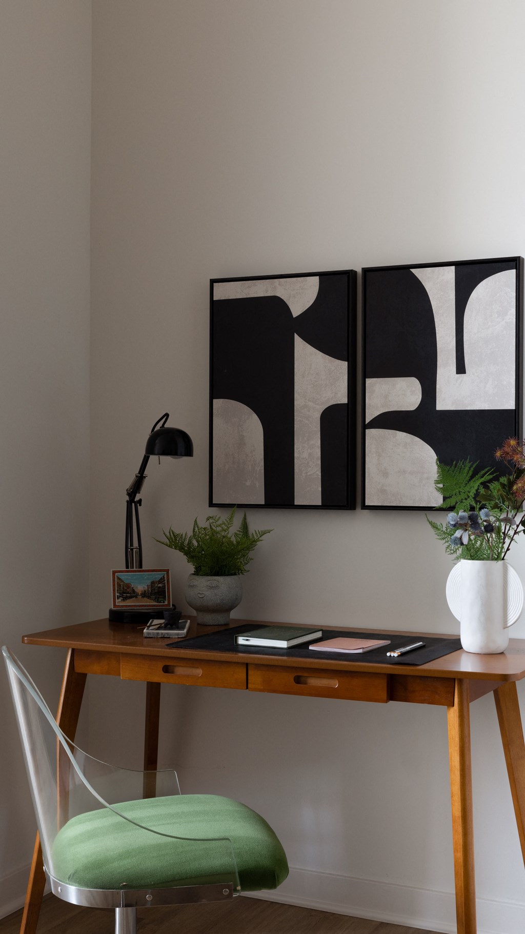 a desk with a green chair and a white vase with plants on it