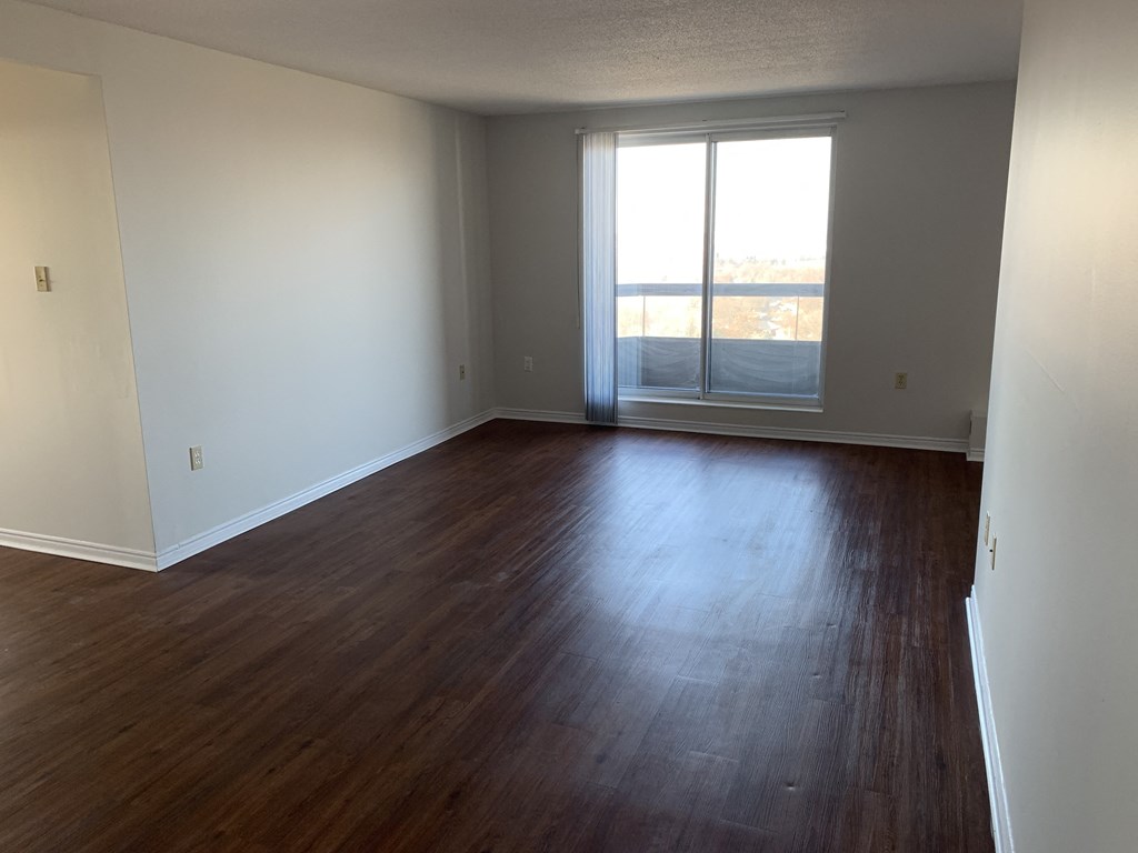 an empty living room with wood floors and a window
