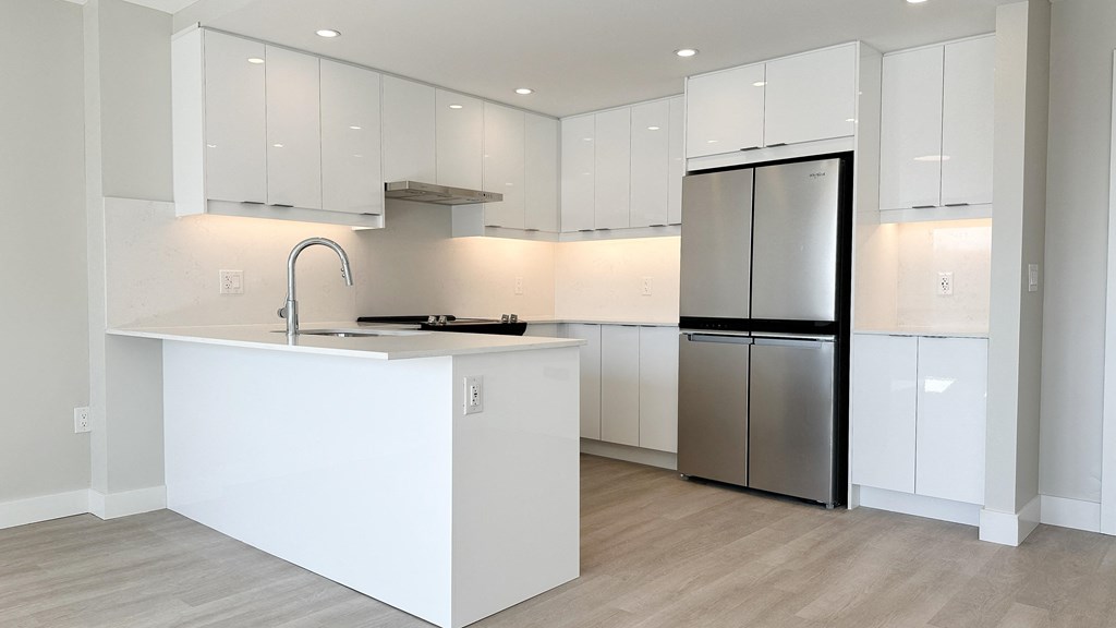 a kitchen with white cabinets and a stainless steel refrigerator