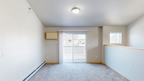 A spacious empty room with a sliding glass door leading to a balcony.