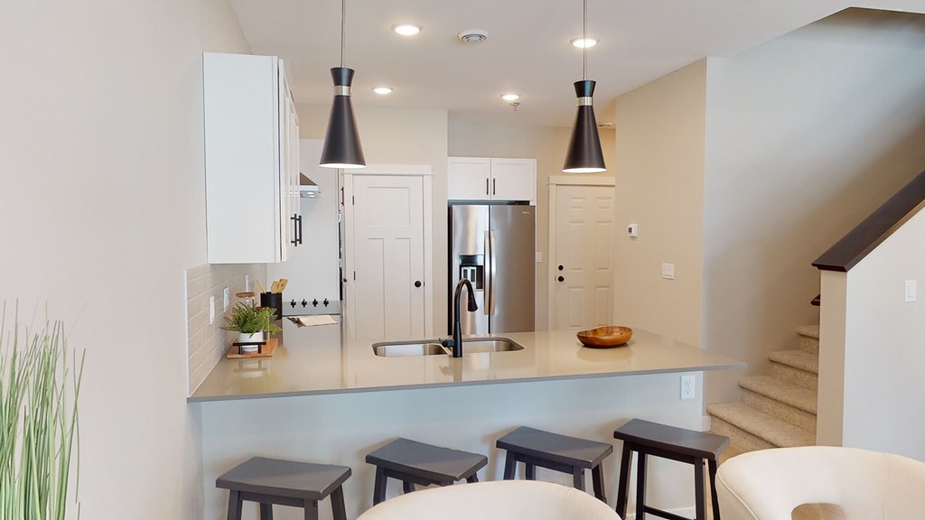 A kitchen with a white counter top and a stainless steel refrigerator.