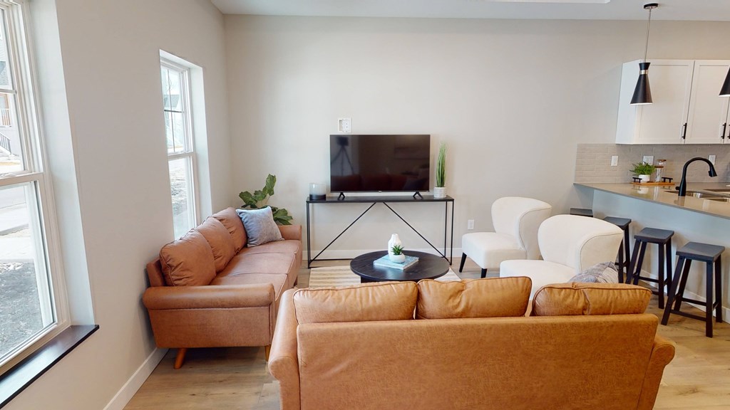 A living room with a television, couches, and a bar area.