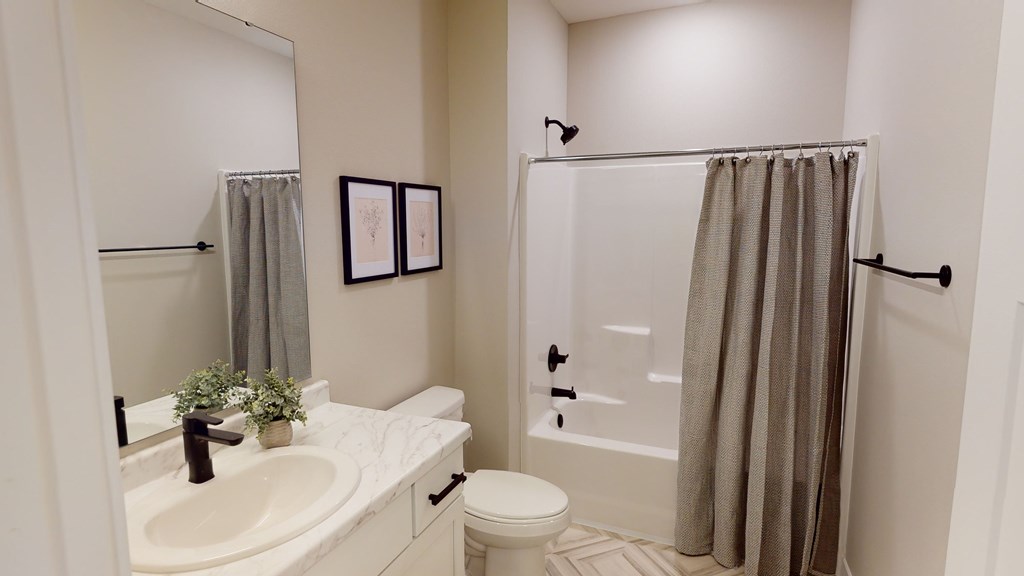 A bathroom with a white sink, toilet, and shower curtain.
