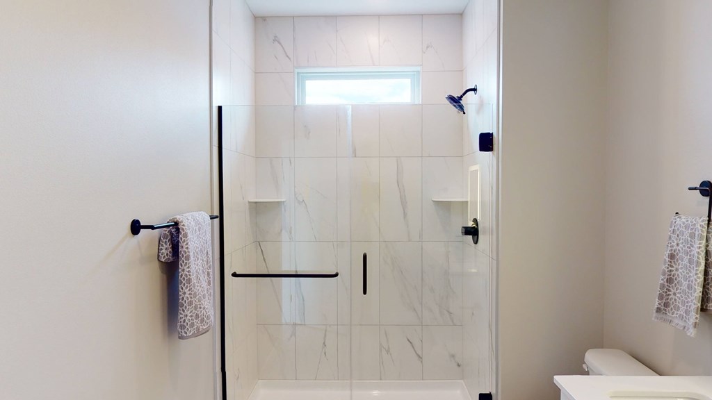 A white bathroom with a glass shower door and a towel rack.