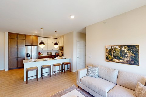 A living room with a couch, bar stools, and a painting on the wall.