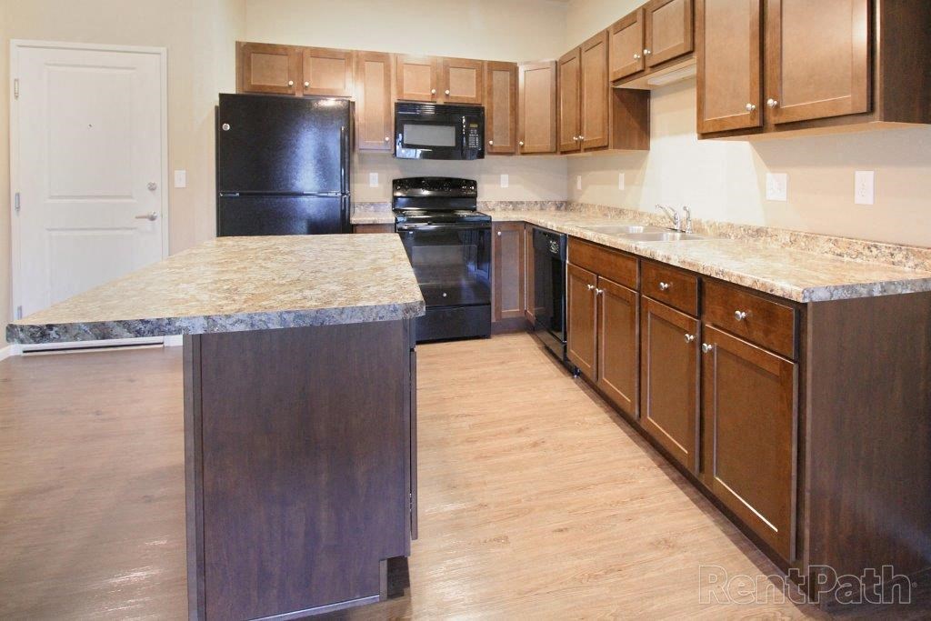 a large kitchen with wooden cabinets and marble counter tops