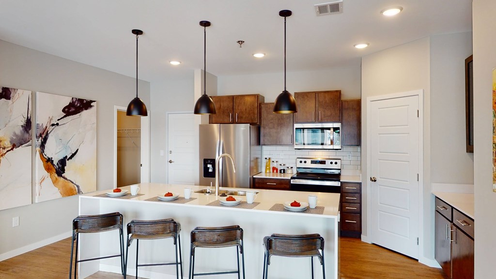 A kitchen with a white counter and bar stools.