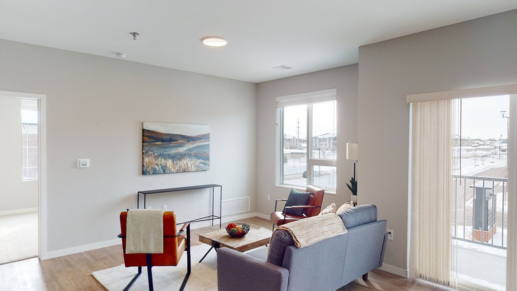 A living room with a blue couch, a red chair, and a painting on the wall.