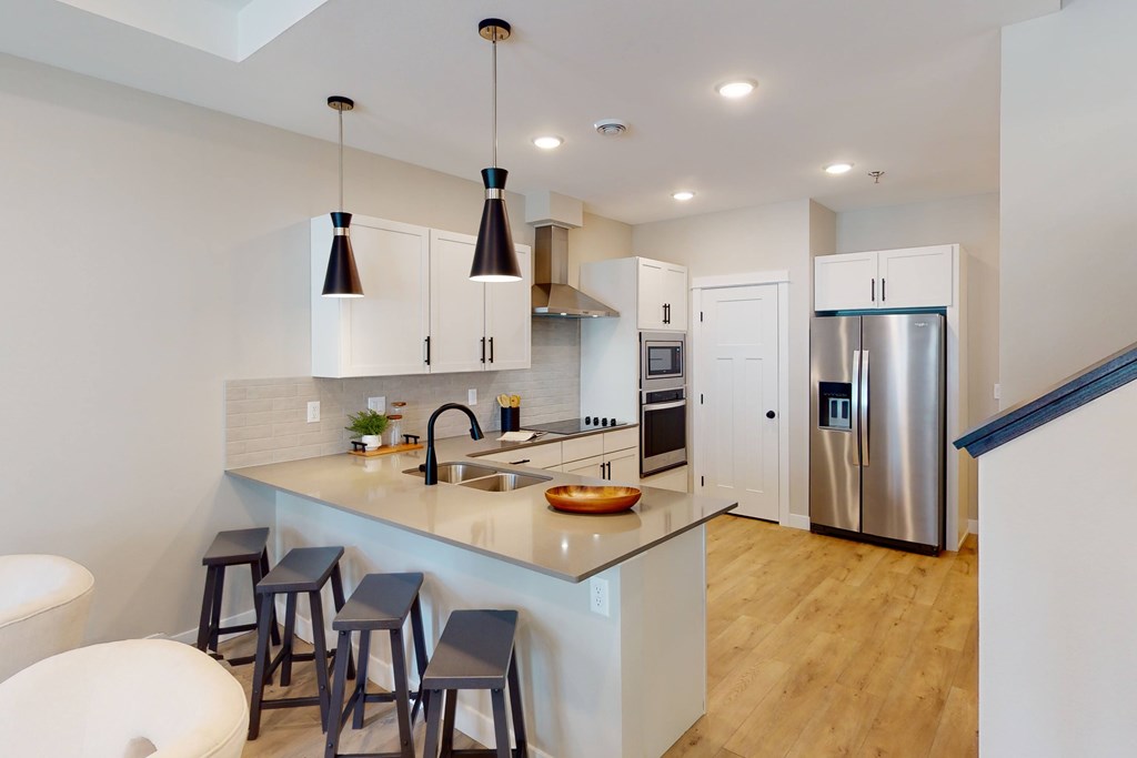 A kitchen with a white counter top and stools.