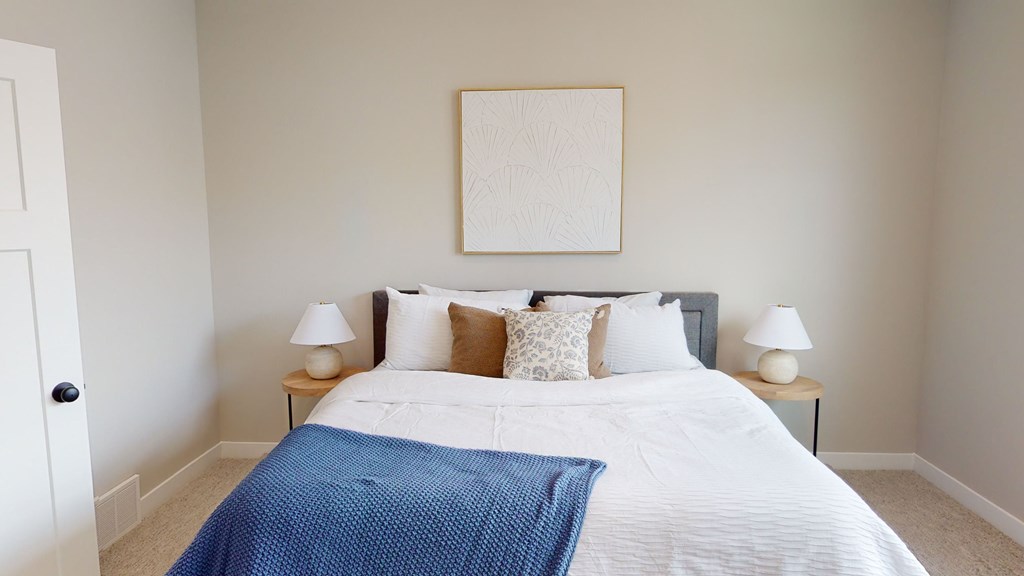 A bedroom with a bed, two nightstands, and a picture on the wall.