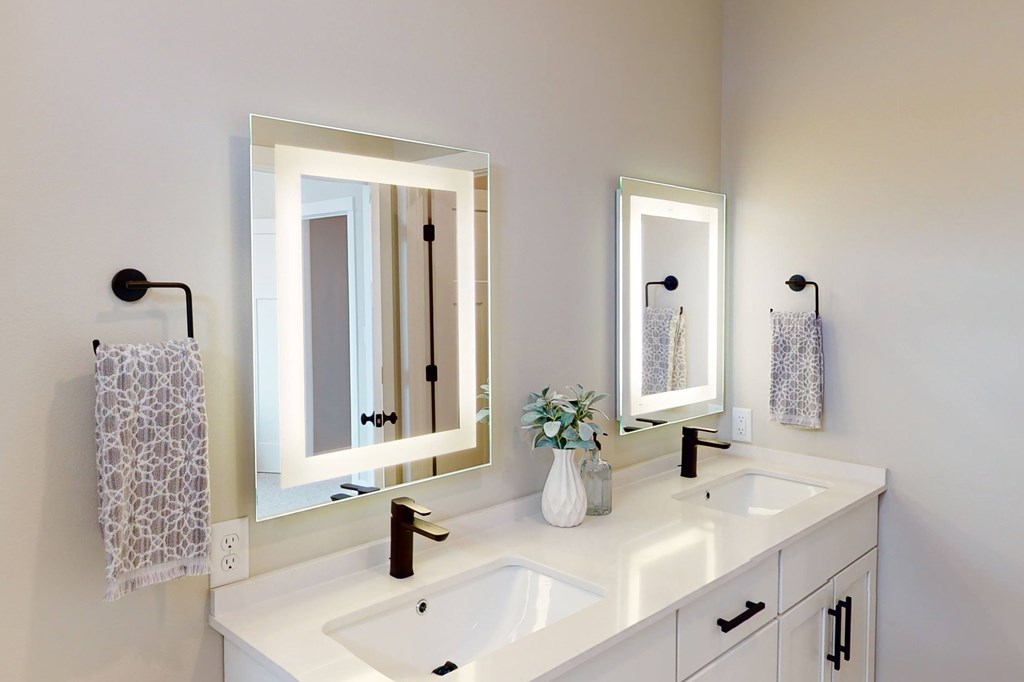 A white bathroom with a sink, mirror, and towel.