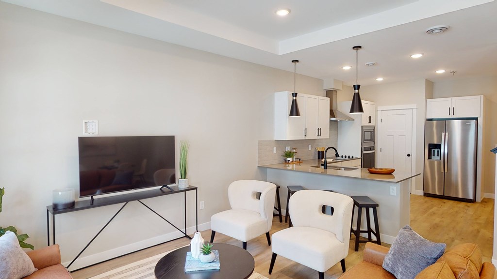 A modern living room with a television, two chairs, and a coffee table.