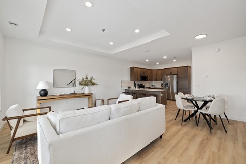 A white couch sits in a modern living room with a dining table and chairs.