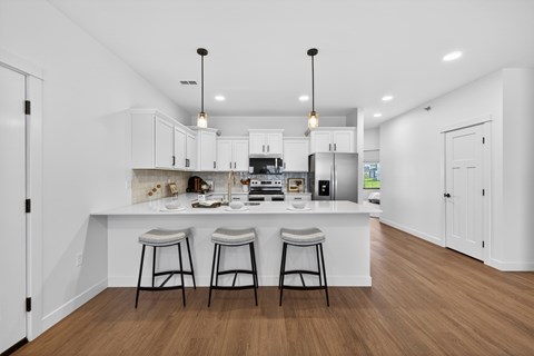 A kitchen with white cabinets and a white island with two stools.