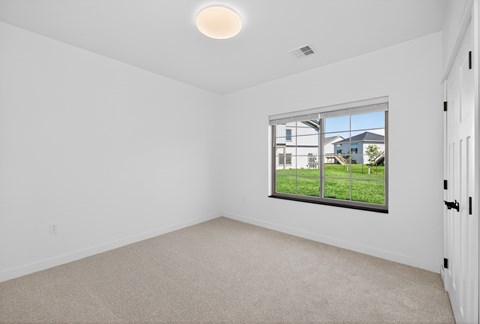 A room with a window showing a view of houses and trees.