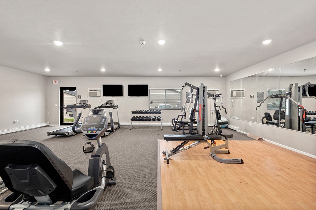 A gym with a variety of equipment including treadmills, weights, and exercise machines.