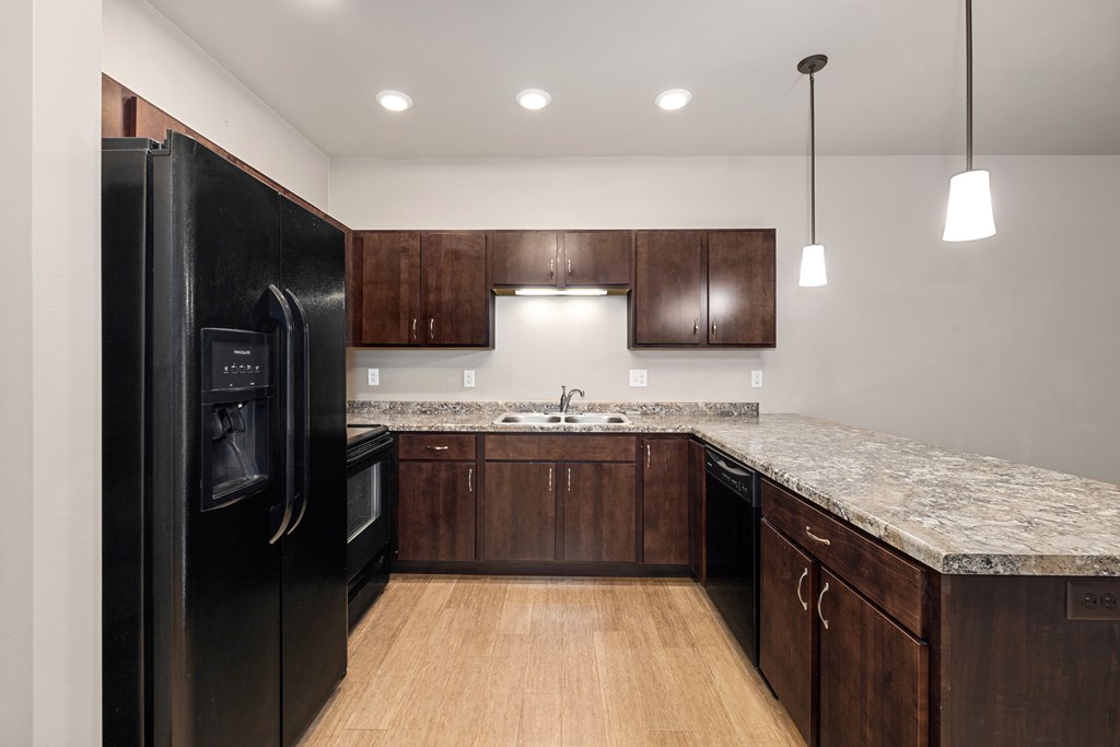 A kitchen with a black refrigerator and wooden cabinets.