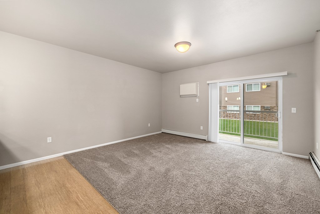 A room with a carpeted floor and a sliding glass door leading to a backyard.