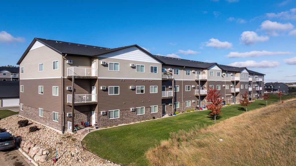 A large apartment complex with multiple balconies and a car parked in front.