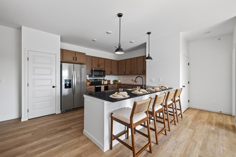A kitchen with wooden chairs and a black countertop.