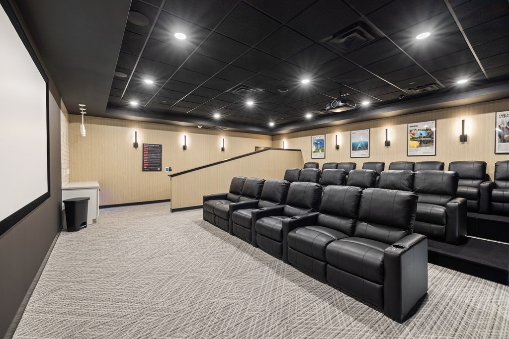 A large room with a carpeted floor and a row of black leather seats.