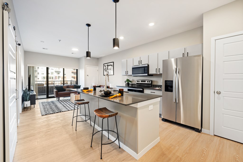 A modern kitchen with a bar stool and a refrigerator.