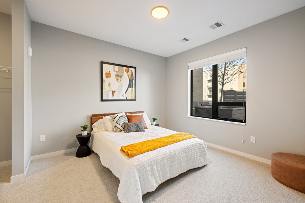 A bedroom with a bed, a small table, and a window.