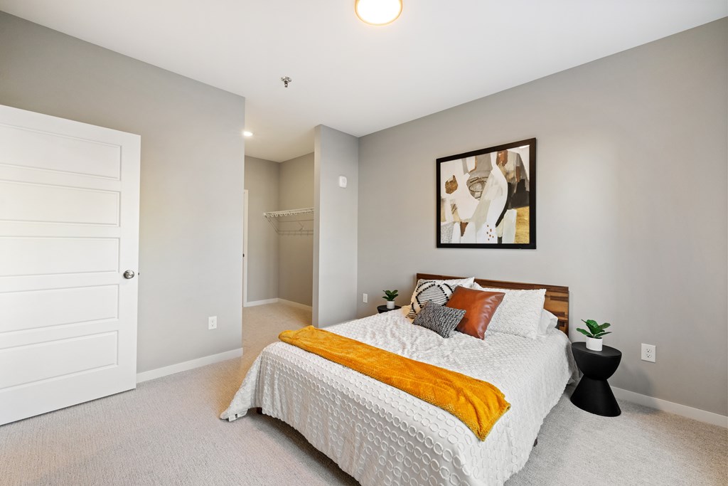 A bedroom with a bed, a painting, and a small table.