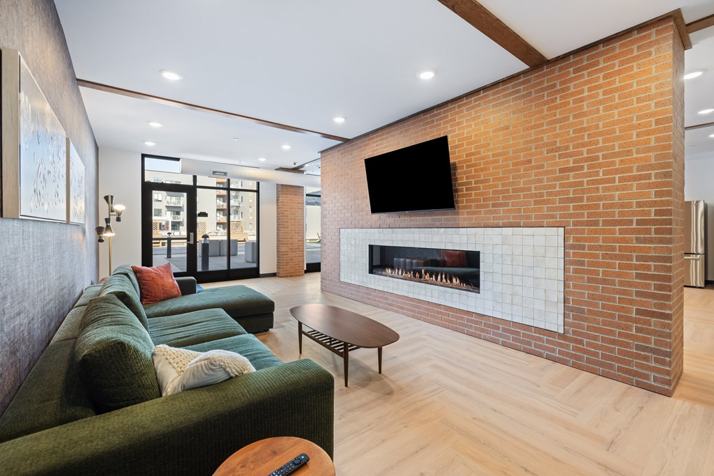 A living room with a green couch and a brick wall.