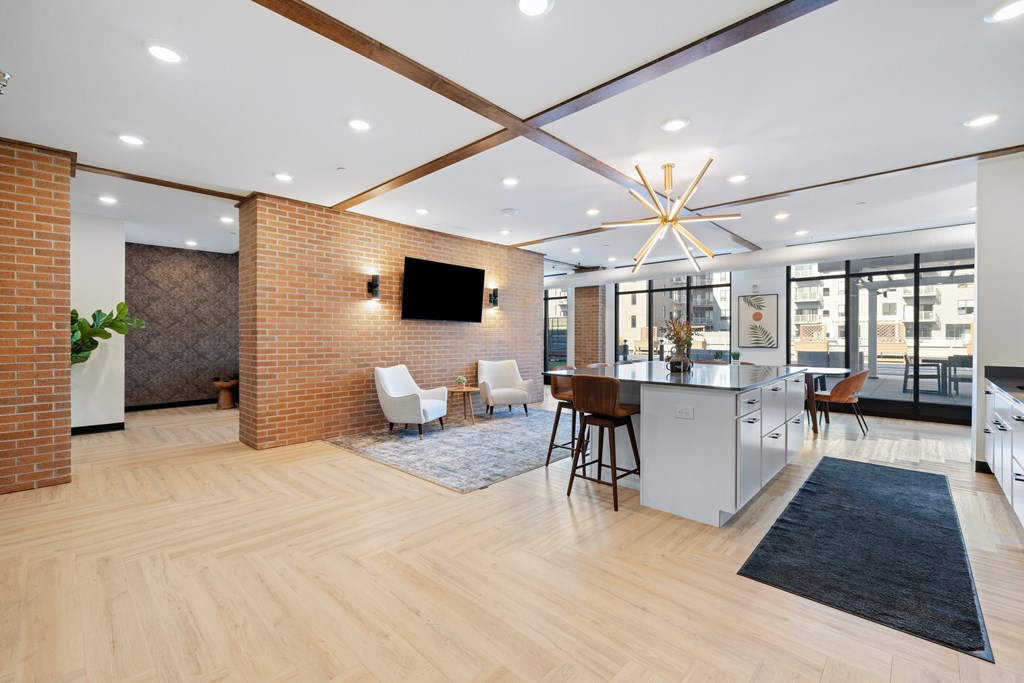 A modern kitchen with a wooden floor and a brick wall.