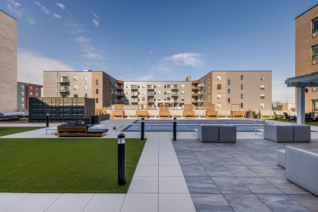 A modern courtyard with a grassy area and benches surrounded by apartment buildings.