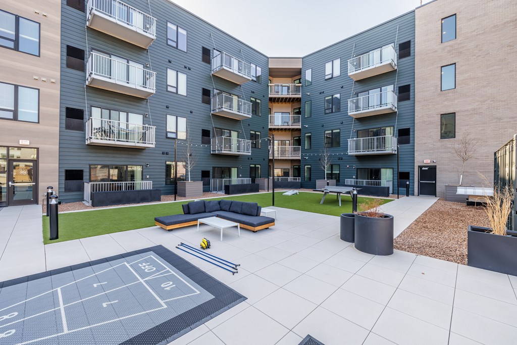 A tennis court is located in the courtyard of a modern apartment complex.