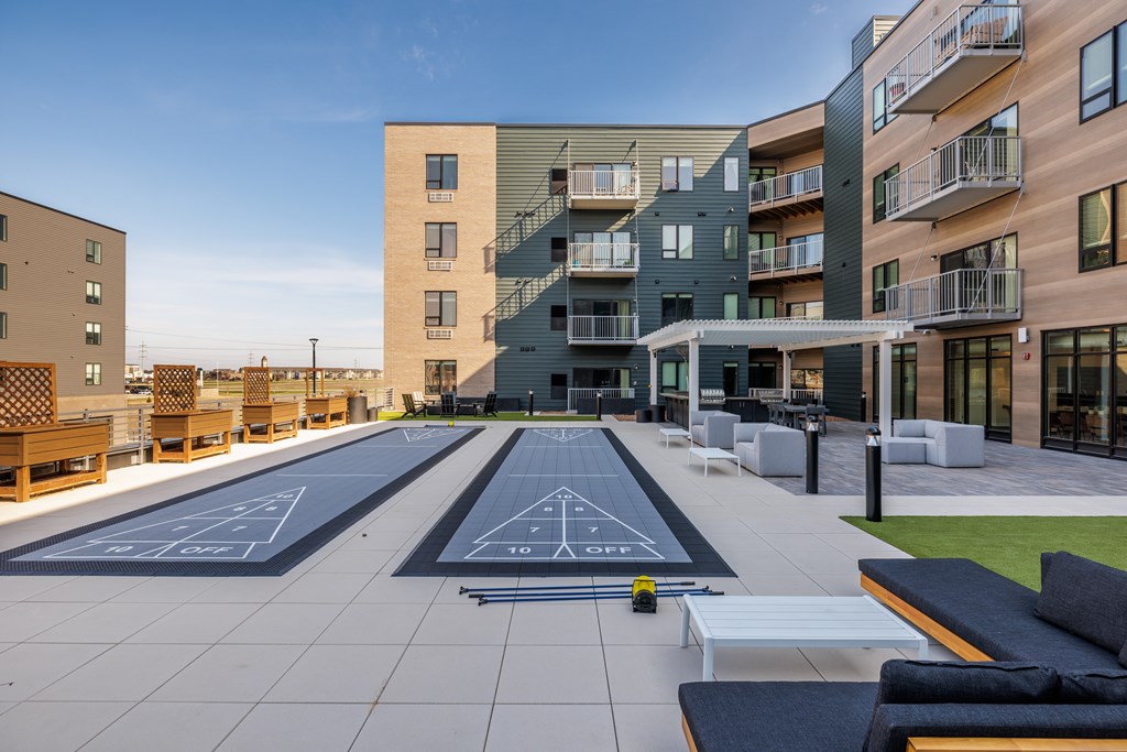A rooftop with a bowling alley and benches in front of apartment buildings.