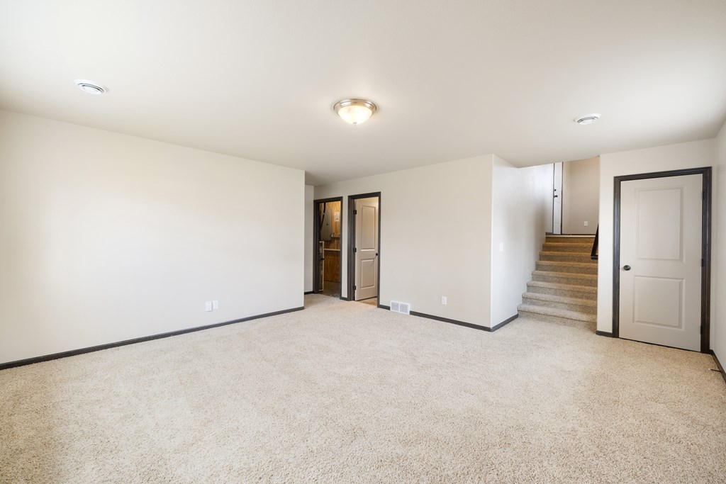 A spacious room with a staircase and a door.