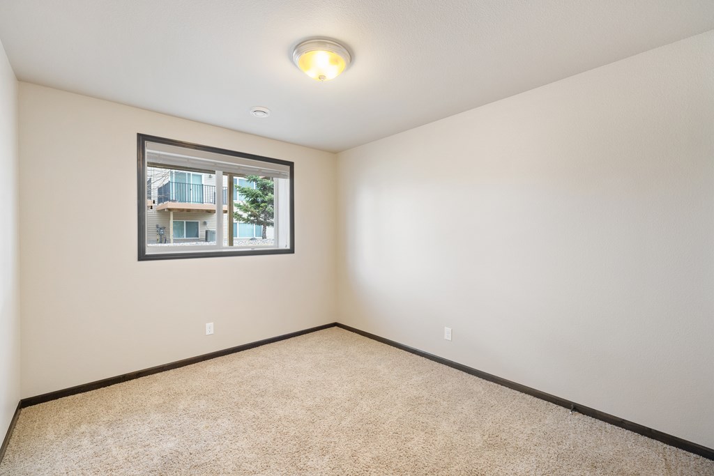 A room with a window and carpeted floor.