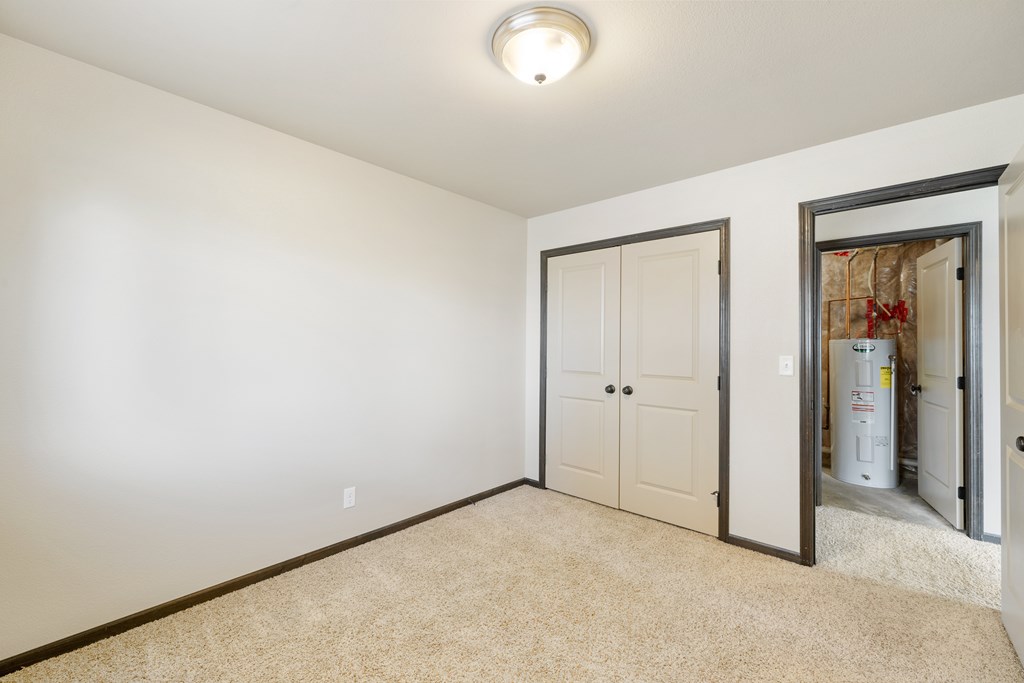 A room with a carpeted floor and a white wall with a door and a window.