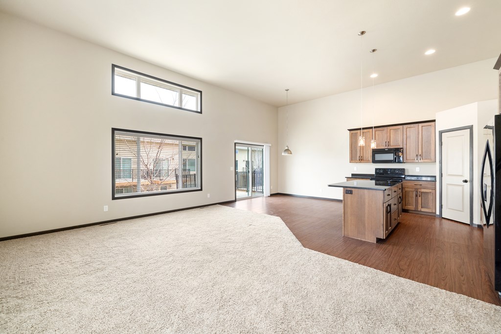 A spacious living room with a kitchen area in the background.