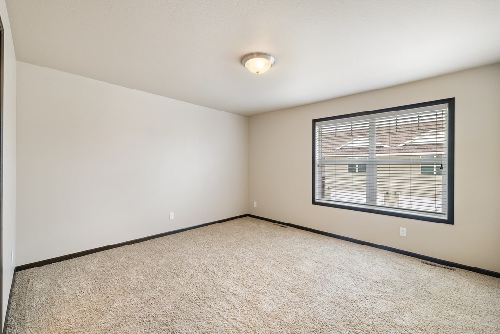A room with a window and carpeted floor.