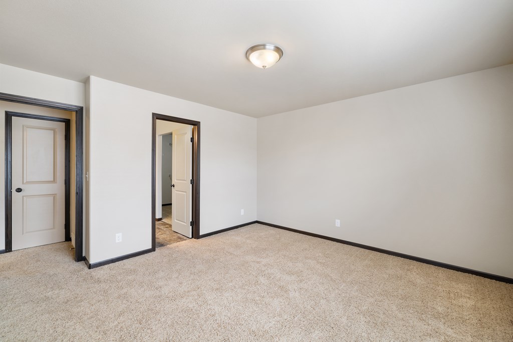 A room with a carpeted floor and two doors.