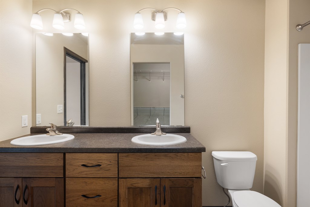 A bathroom with a toilet, sink, and mirror.