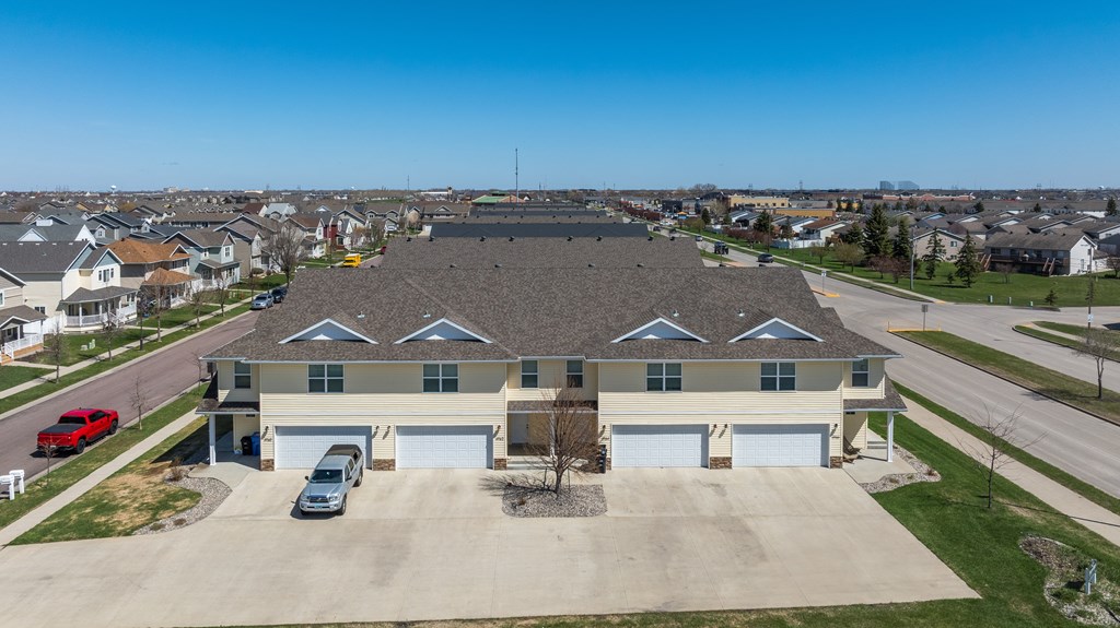 A large house with a grey roof and a red car in front.