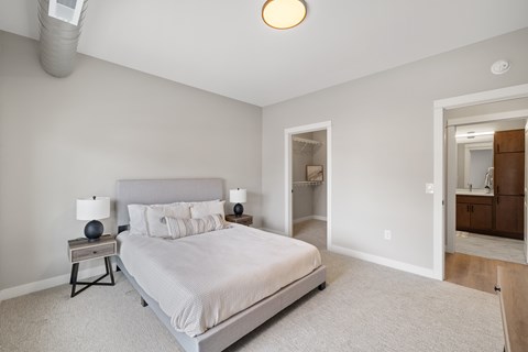 A bedroom with a large bed and a nightstand with a lamp.