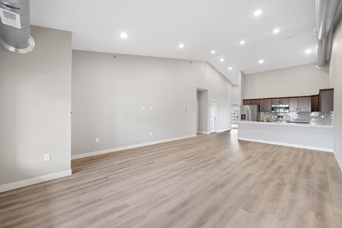 A spacious room with wooden flooring and white walls.