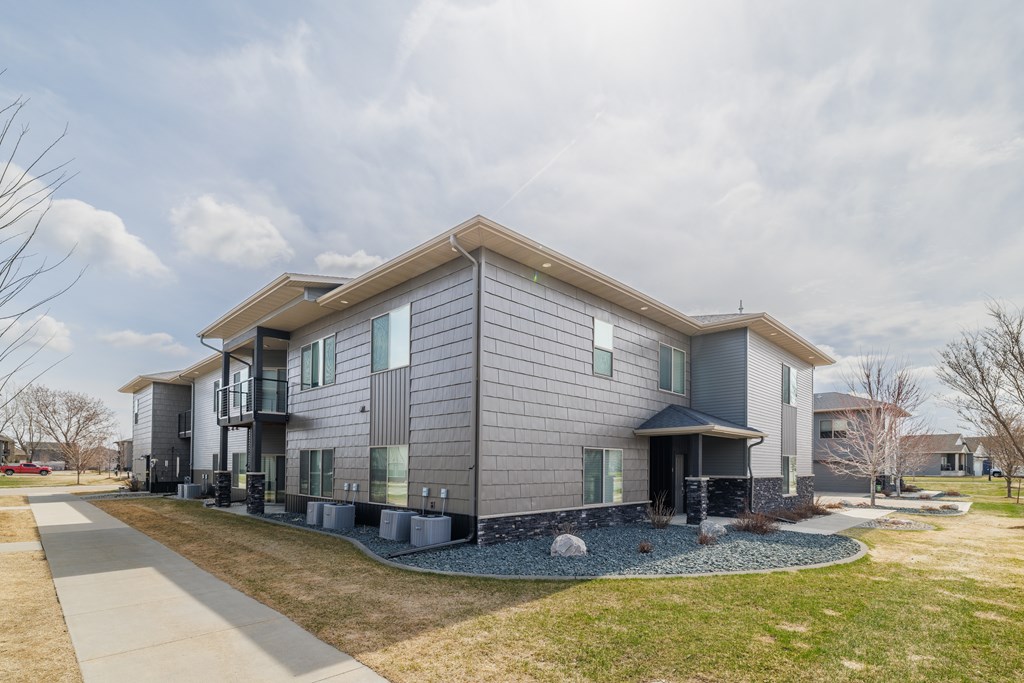 A modern house with a grey facade and a stone pathway leading to the entrance.
