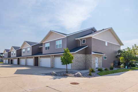 A large, modern house with a grey and brown exterior and a white garage door.