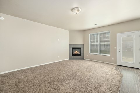 A spacious living room with a fireplace and a carpeted floor.