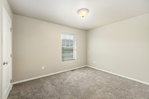 A room with a carpeted floor and a window.