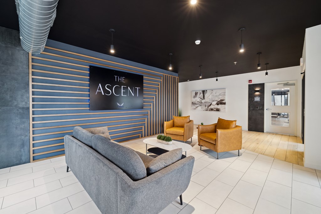 A room with a sofa and two lounge chairs and sign that says The Ascent.