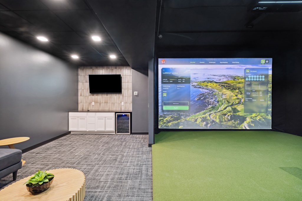 A golf simulator room with a large screen and tv.